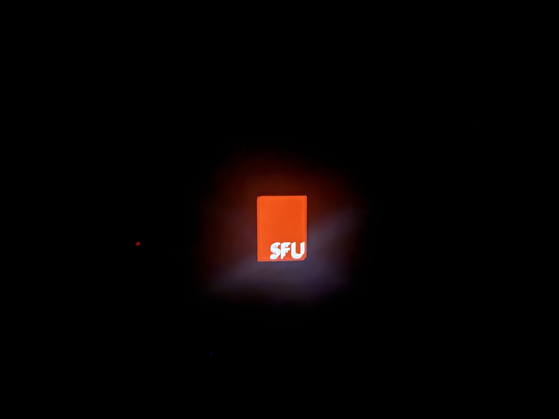 Thermostat cover glowing red with an SFU mark at night